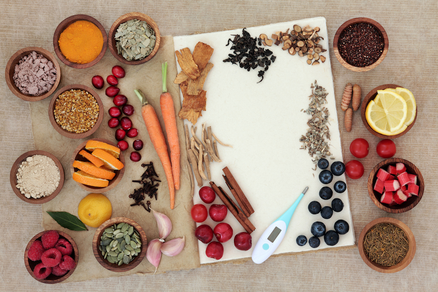 Food selection for cold and flu cure to boost immune system with thermometer, high in vitamins, anthocyanins, antioxidants and minerals in wooden bowls over white background.