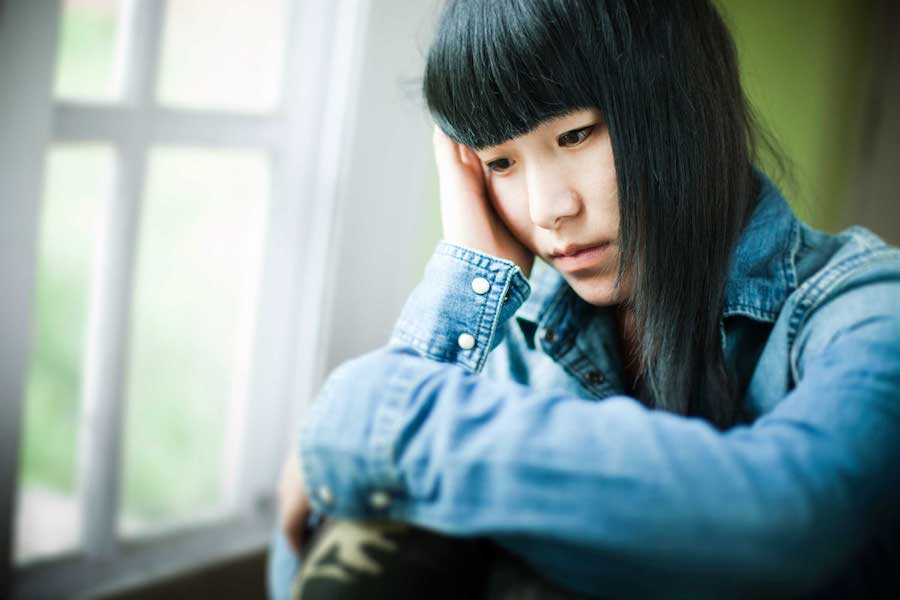 Depressed looking woman with bangs and jean jacket